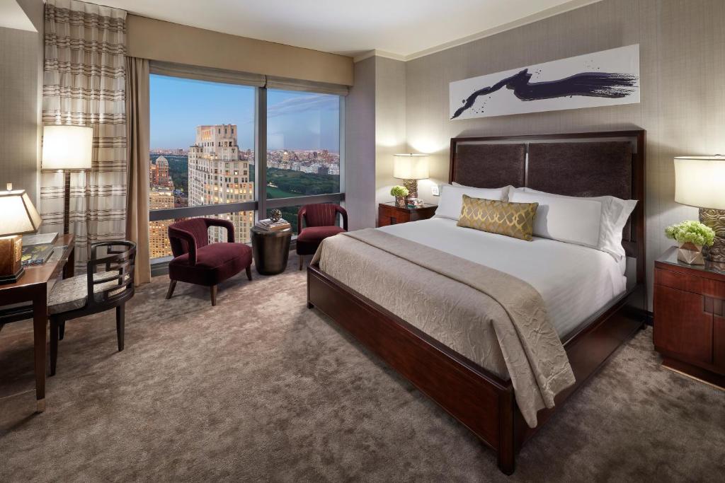 a hotel room with a bed and a desk and a large window at Mandarin Oriental, New York in New York