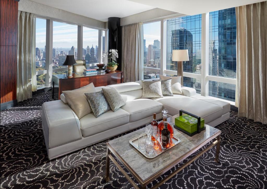a living room with a white couch and large windows at Mandarin Oriental, New York in New York