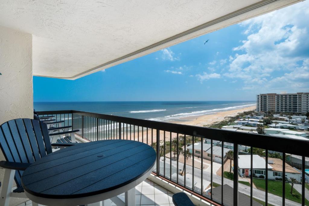 a balcony with a blue chair and a view of the beach at Sunrise beach views with top complex amenities and pool access! in Ormond Beach
