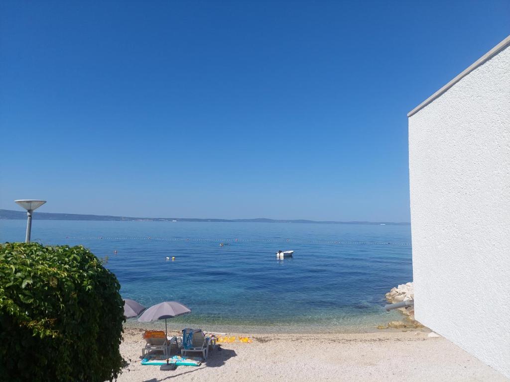 a beach with chairs and umbrellas in the water at Apartman Draga in Podstrana