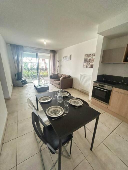 Il comprend un salon avec une table et des chaises ainsi qu'une cuisine. dans l'établissement T3 proche Montpellier centre, à Montpellier