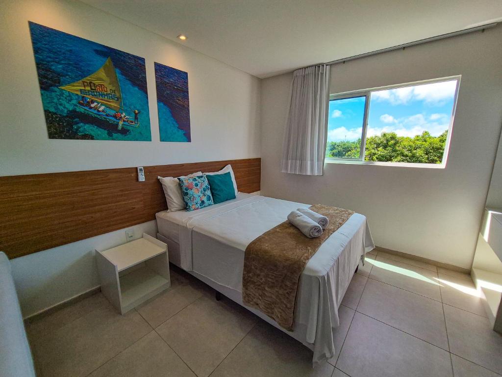 a bedroom with a bed and a window at Porto Vila by AFT in Porto De Galinhas