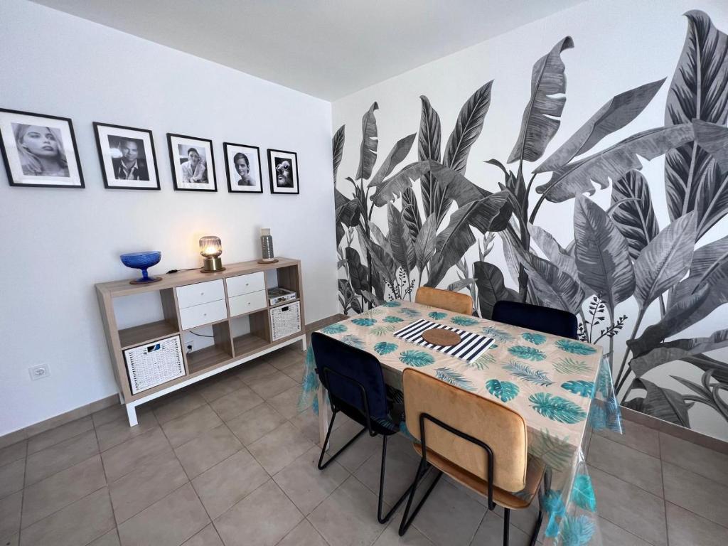 une salle à manger avec une table et une fresque végétale dans l'établissement Le Cosy Rionde : Apt 6 Prs, 2 ch, parking, clim, à Antibes