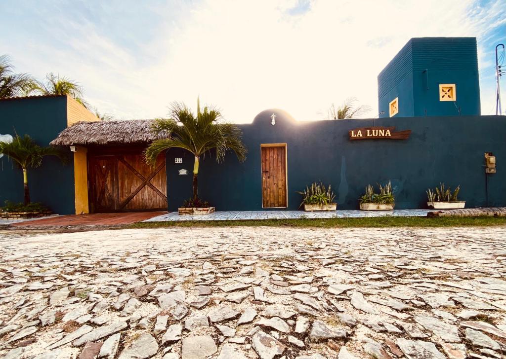 a blue building with a stone road in front of it at Pousada La Luna in Paracuru