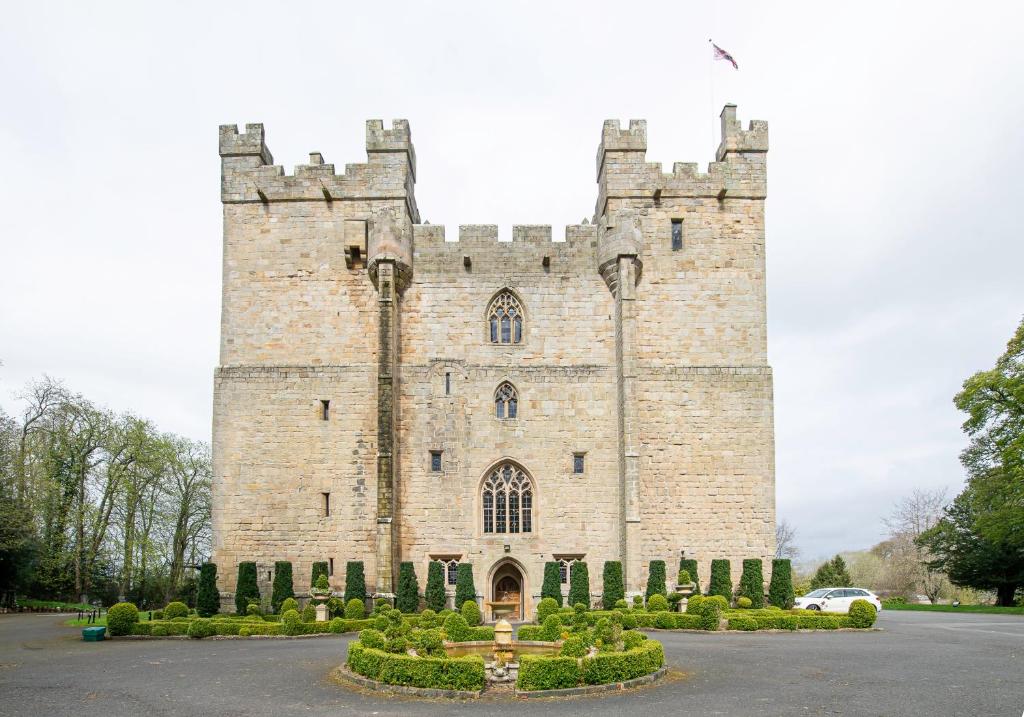 een groot stenen kasteel met struiken ervoor bij Langley Castle Hotel in Hexham