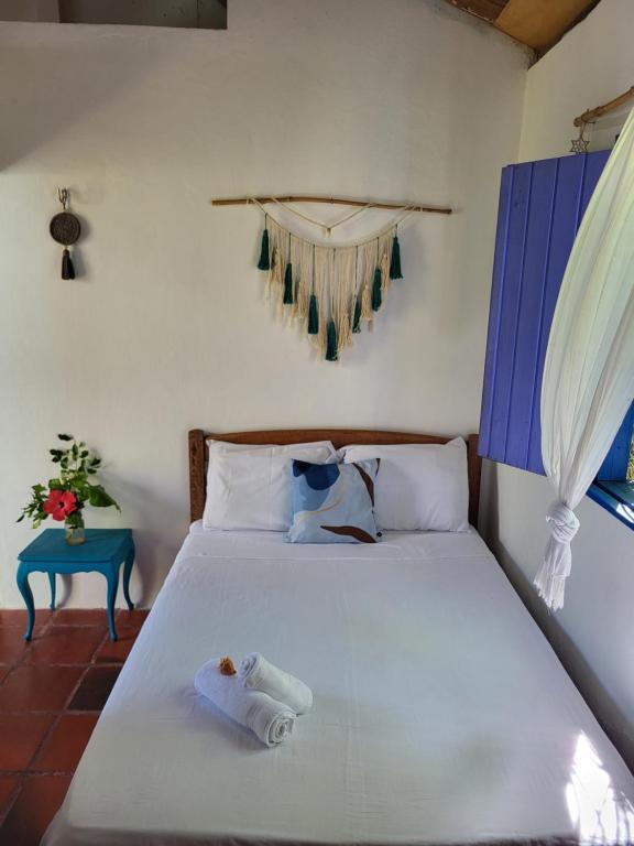 1 dormitorio con cama blanca y mesa azul en Chalé Flor do ser, en Canoa Quebrada