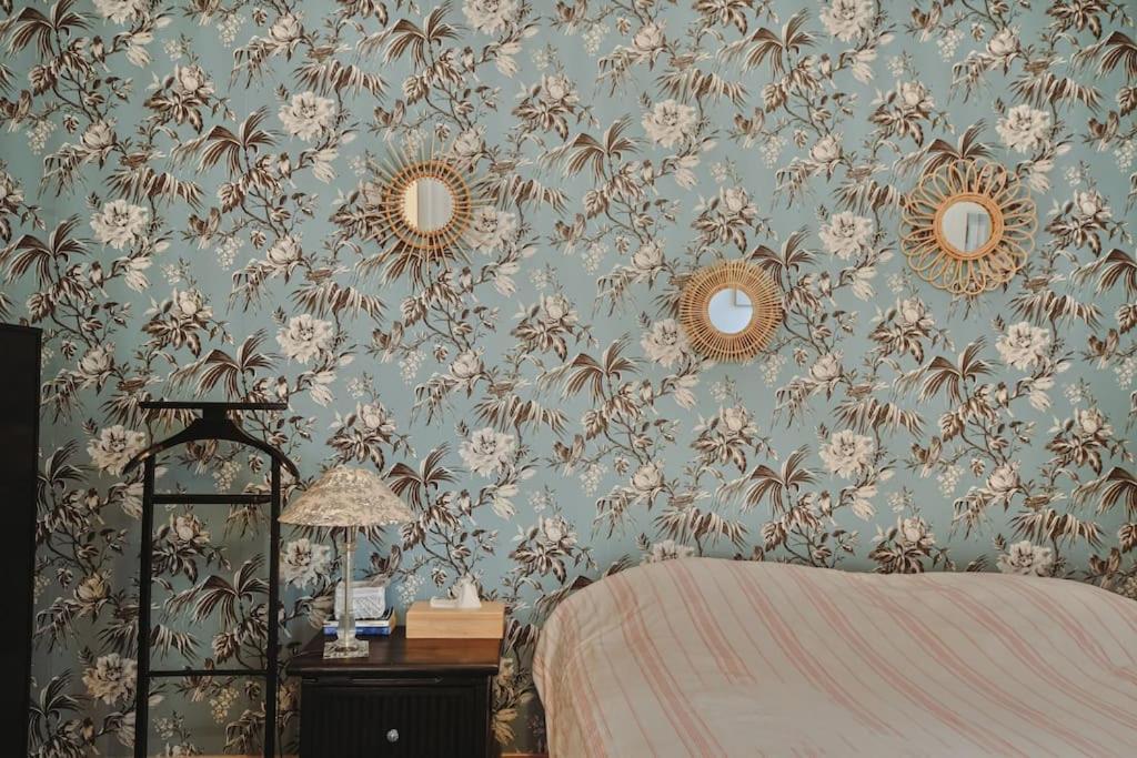 une chambre avec du papier peint floral bleu avec un lit et des miroirs dans l'établissement Charmant appartement proche du centre avec grande terrasse, à Strasbourg
