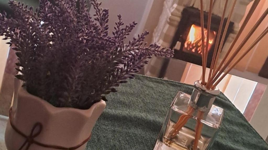 een tafel met een vaas met paarse bloemen en een kaars bij Apartament Borsec in Borsec