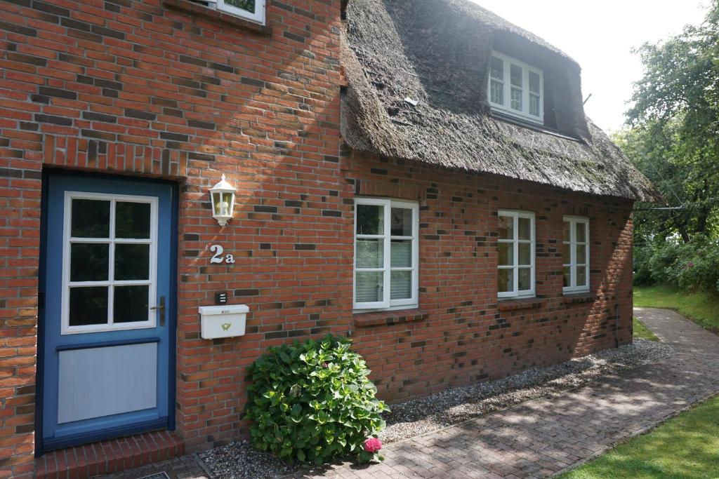 a brick house with a blue door and a window at Friisk Aran in Alkersum
