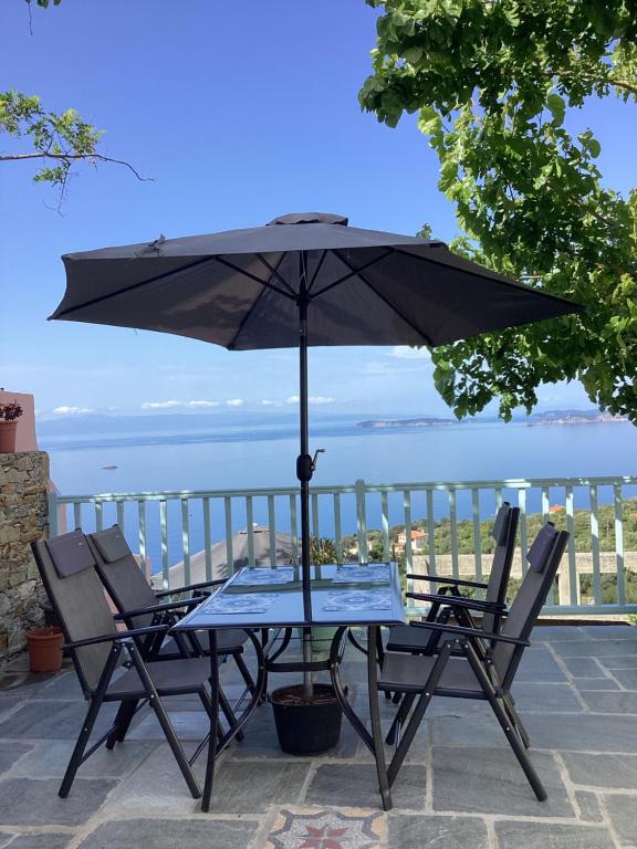 un tavolo e sedie con ombrellone su un patio di Διώροφη κατοικία Γλώσσα Σκοπέλου a Skopelos Town