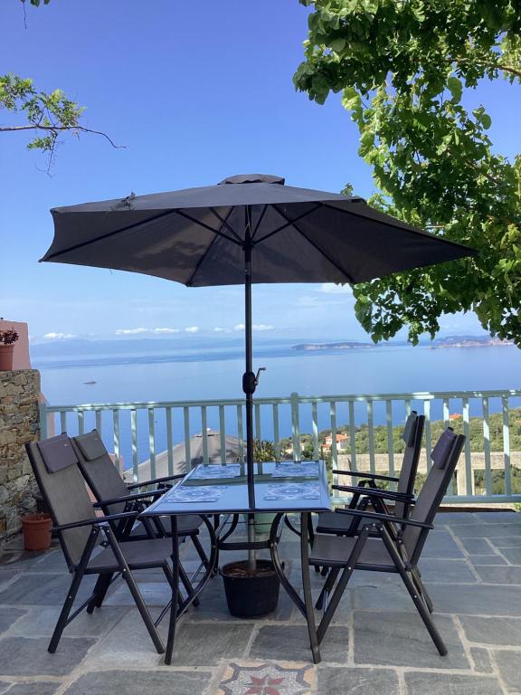 a table and chairs with an umbrella on a patio at Διώροφη κατοικία Γλώσσα Σκοπέλου in Skopelos Town