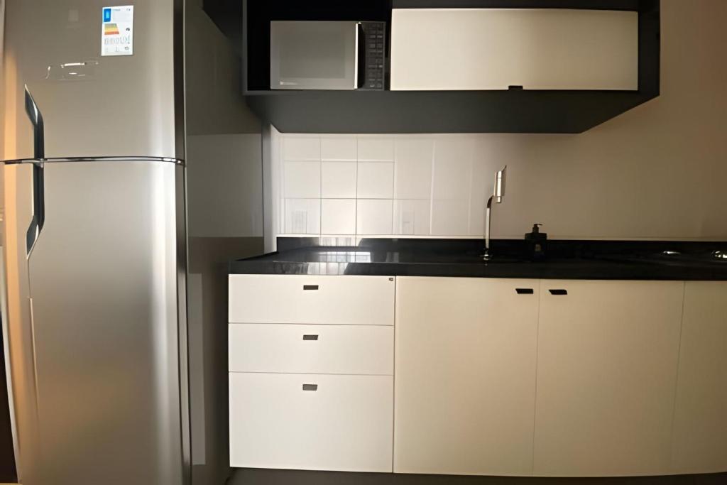 een keuken met witte kasten en een roestvrijstalen koelkast bij Morcelli Mobiliados - Uniqo Smart Living in Santa Maria