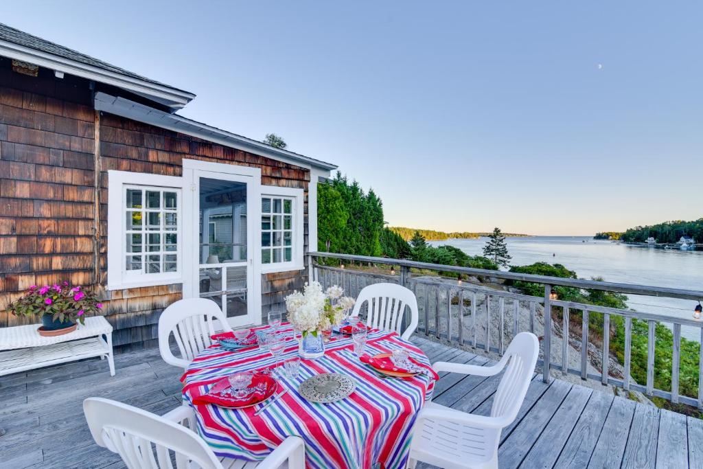 a table and chairs on a deck with a view of the water at Oceanfront Cottage with Deck 2 Mi to Boothbay Harbor in West Boothbay Harbor
