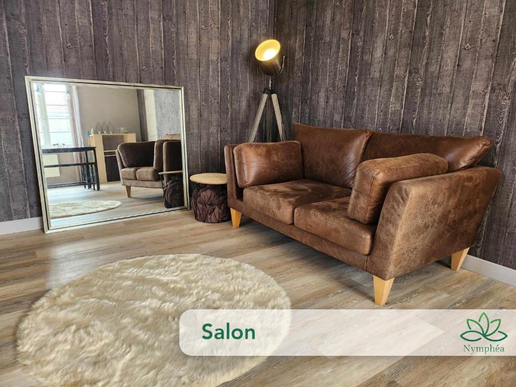 een woonkamer met een bruine bank en een spiegel bij Logement cocooning 2-4 personnes avec Salle de jeux in Chémery