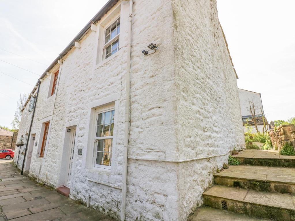 a white brick building with a door and stairs at Katie's Cottage in Skipton