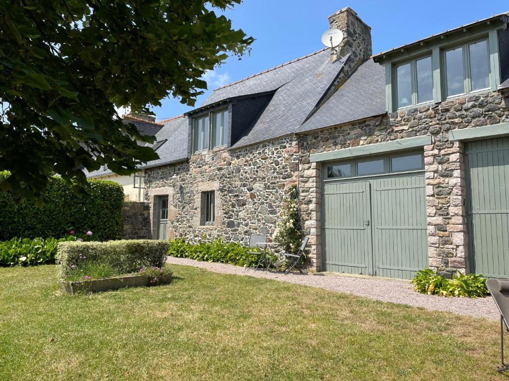een stenen huis met twee garagedeuren in een tuin bij La Ferme Cap Fréhel in Hénanbihen