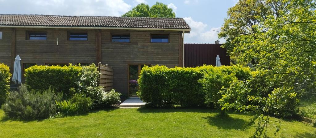 uma casa de tijolos com um quintal com arbustos em Camellia em Cherbonnières