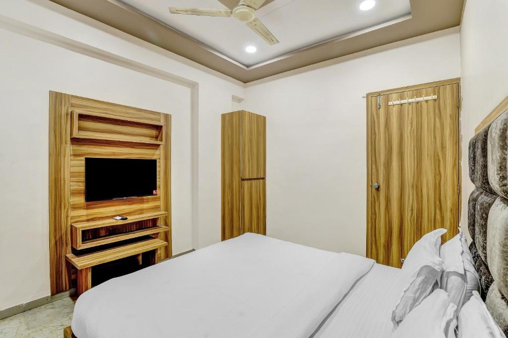 1 dormitorio con 1 cama y TV de pantalla plana en Capital O Hotel Maple View en Naroda