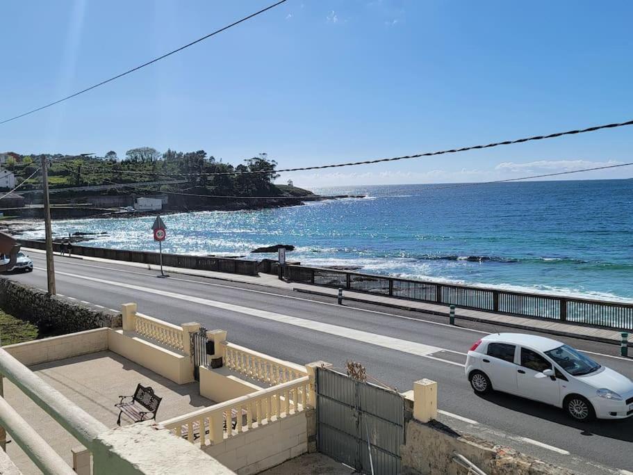 a white car parked on a road next to the ocean at Ventana al Atlantico - House across from the beach in Porto do Son