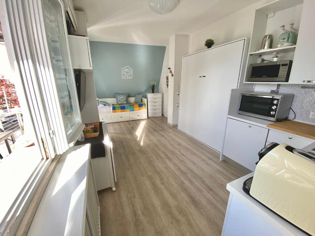 una cucina con armadietti bianchi e pavimenti in legno massello di La Casa di Pamy a Bellaria-Igea Marina