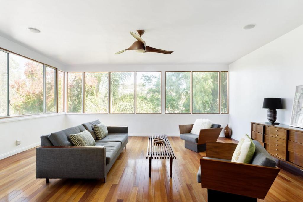 a living room with a couch and chairs and windows at Silver Lake Mid-century Nestled In The Treetops in Los Angeles