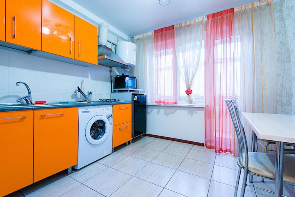 uma cozinha com armários laranja e uma máquina de lavar roupa em Studiominsk 15 Apartments em Minsk