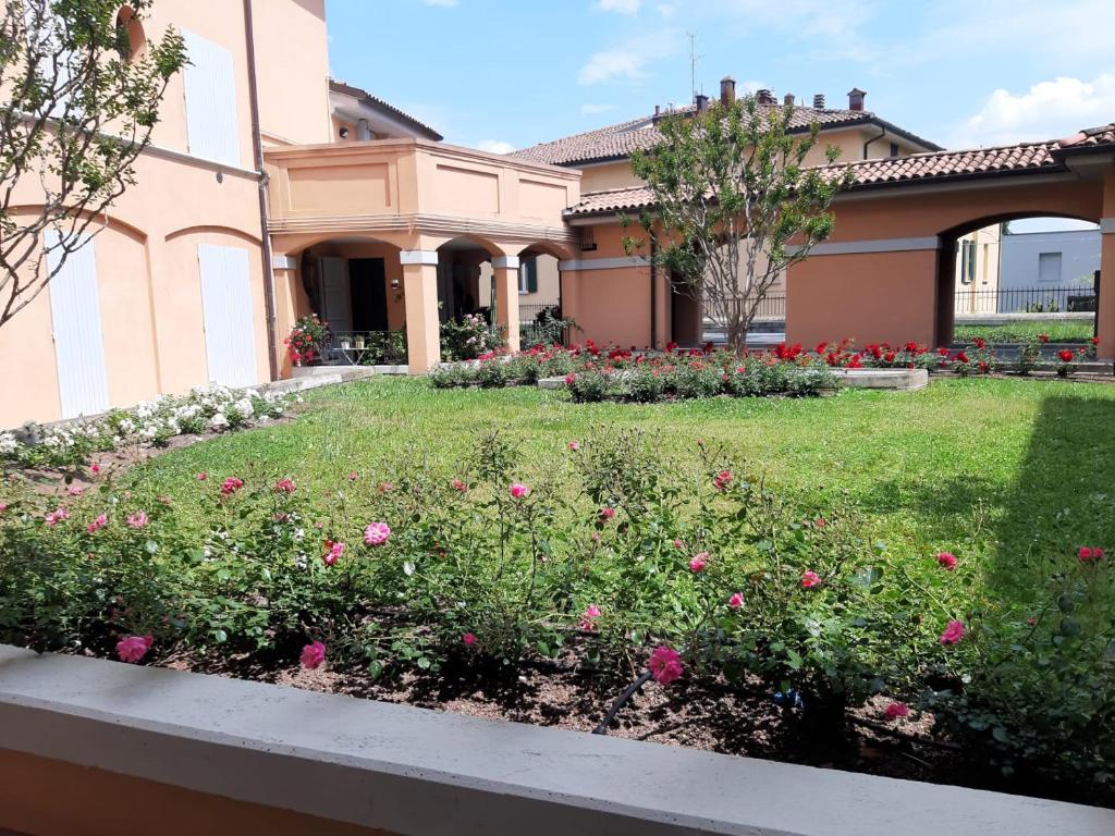 um jardim com flores cor-de-rosa em frente a um edifício em A Casa San Pietro - bilocale centro storico - Cyclist-friendly em Castel San Pietro Terme