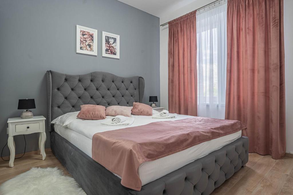 ein Schlafzimmer mit einem großen Bett mit rosa Kissen in der Unterkunft KARINA APARTMAN in Dunajská Streda