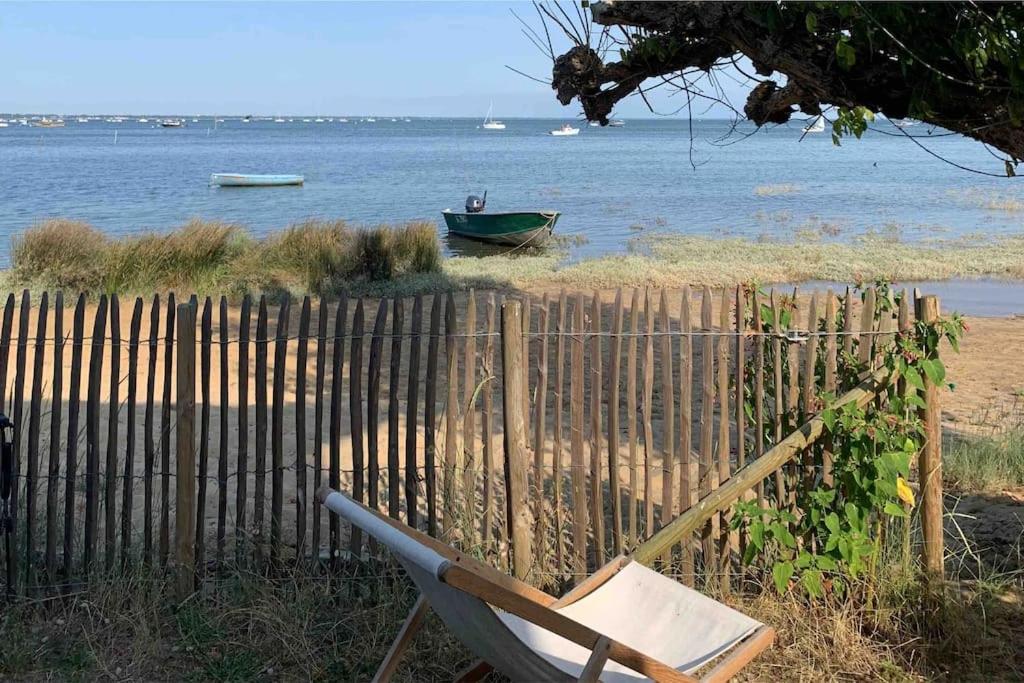 une chaise assise sur la plage à côté d'une clôture dans l'établissement La maison Piclaouey, à Lège-Cap-Ferret