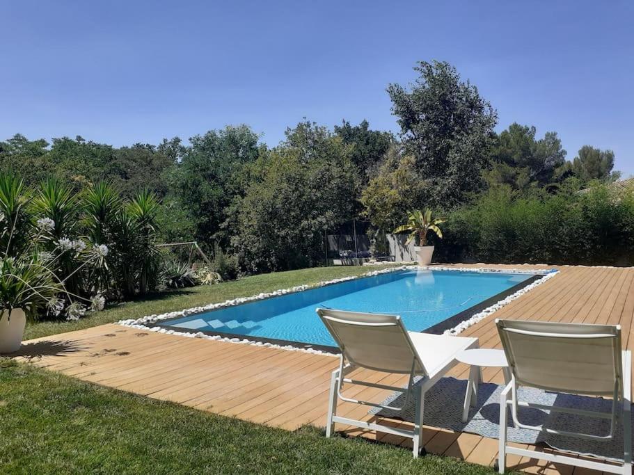 - une piscine dans un jardin avec 2 chaises et une table dans l'établissement Belle villa 10 pers dans le sud de la France, à Sommières