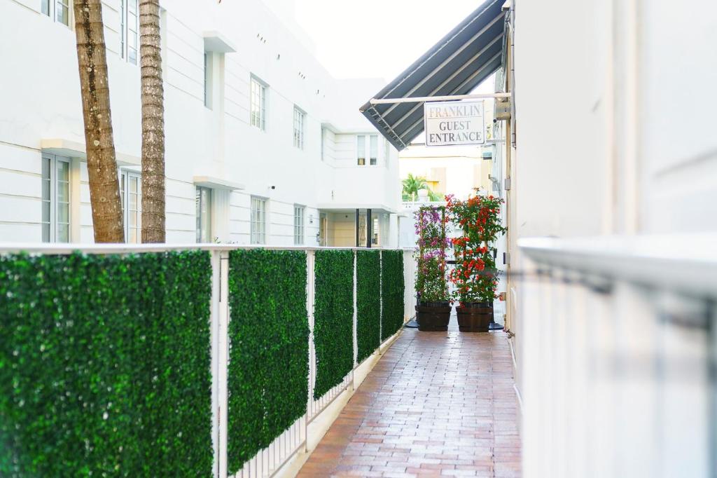 a walkway in front of a building with green hedge at Franklin Suites South Beach in Miami Beach