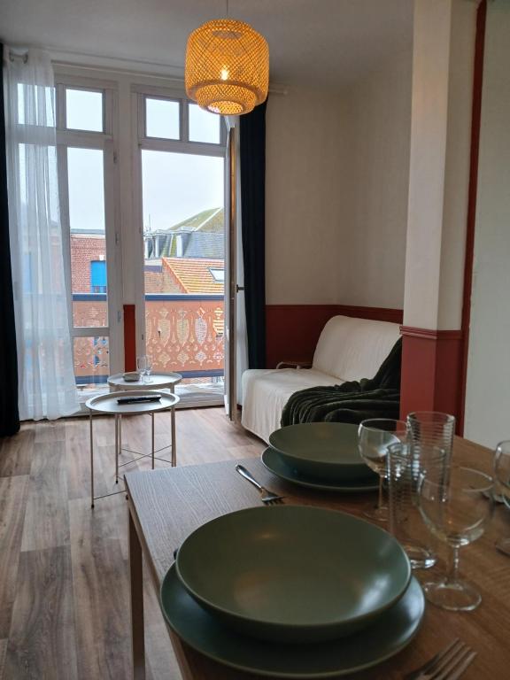 un salon doté d'une table avec des assiettes vertes dans l'établissement Appartement avec beau balcon, à Mers-les-Bains