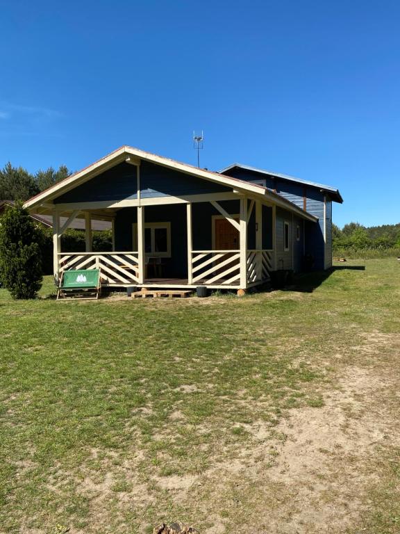a house with a porch on a grass field at Sosenkowe Zacisze in Ciche