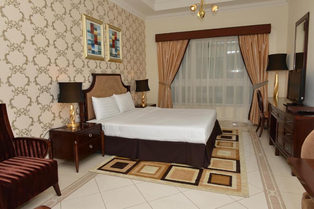 a bedroom with a bed and a television and a couch at Al Manar Hotel Apartments in Dubai