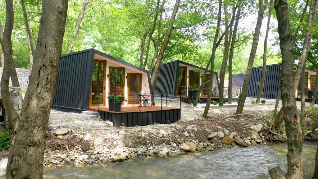 ein Haus im Wald neben einem Fluss in der Unterkunft Hotel Blisku do gradot in Skopje