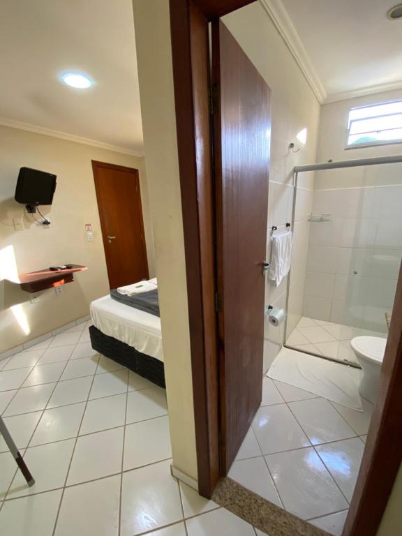 アラクルスにあるBuriti Hotel - Barra do Riacho, Aracruz ESのバスルーム(トイレ、シャワー付)、ベッド1台が備わります。