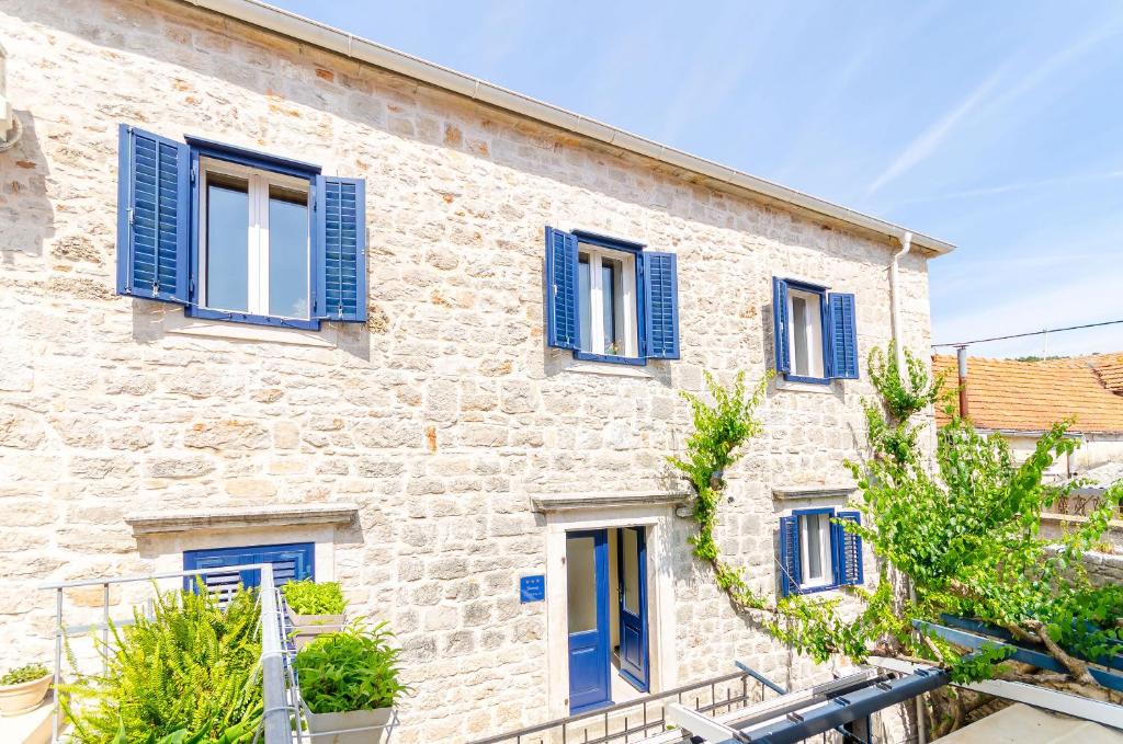 a stone building with blue shutters on it at Apartment City Center in Jelsa