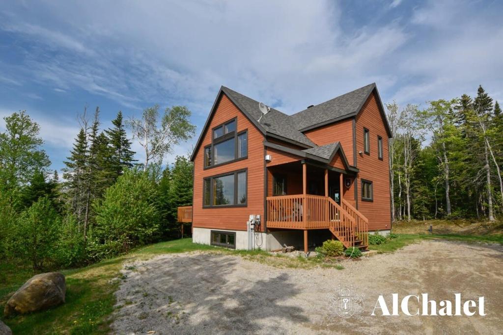 una grande casa in legno con un ampio ponte di B-Évasion Chalet avec spa sauna a Petite-Rivière-Saint-François