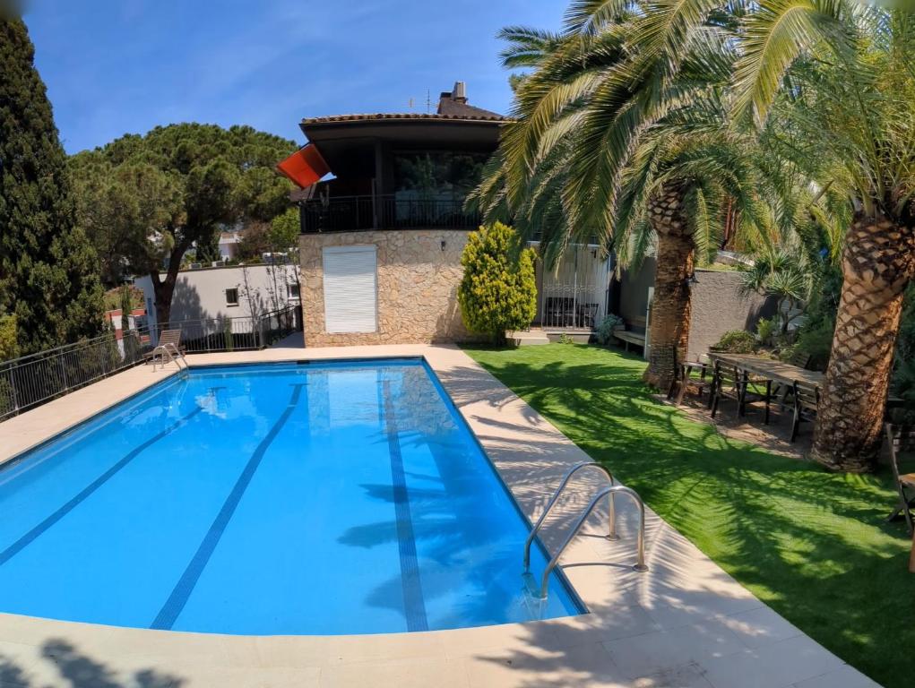 ein Swimmingpool vor einem Haus mit Palmen in der Unterkunft Villa Zen Costa Brava in Lloret de Mar