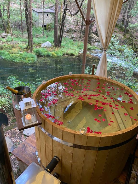 a wooden barrel filled with flowers in front of a river at Wild Glamping Portugal a glamorous camping to relax in Viana do Castelo in Viana do Castelo