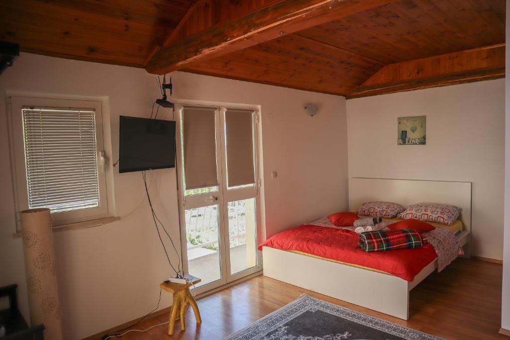 a bedroom with a red bed and a window at Guest House Godimento in Čilipi