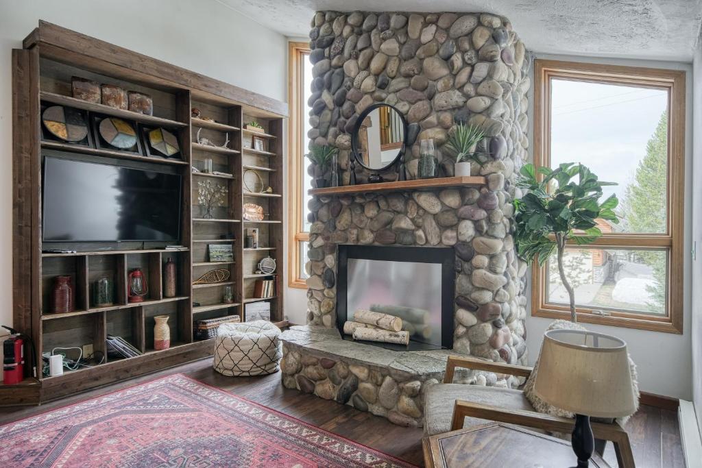 a living room with a stone fireplace and a television at Wapiti View 6-Bedroom Cabin 28mins to Yellowstone in Island Park