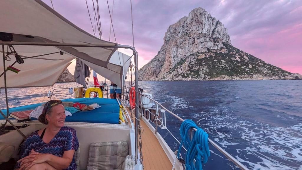 a woman sitting on the back of a boat with a mountain at Alójate en un Velero en Ibiza in Illes Balears