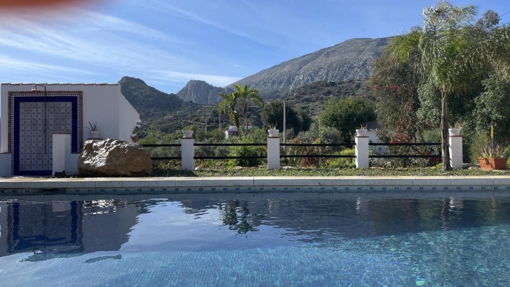 una casa con una piscina con una montaña en el fondo en Finca Valle Verde en Alora