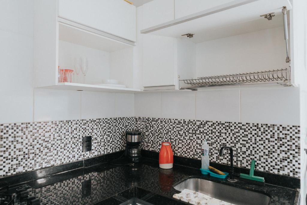 uma cozinha com armários brancos e um lavatório em Recanto Kitnet em Lagoa Santa