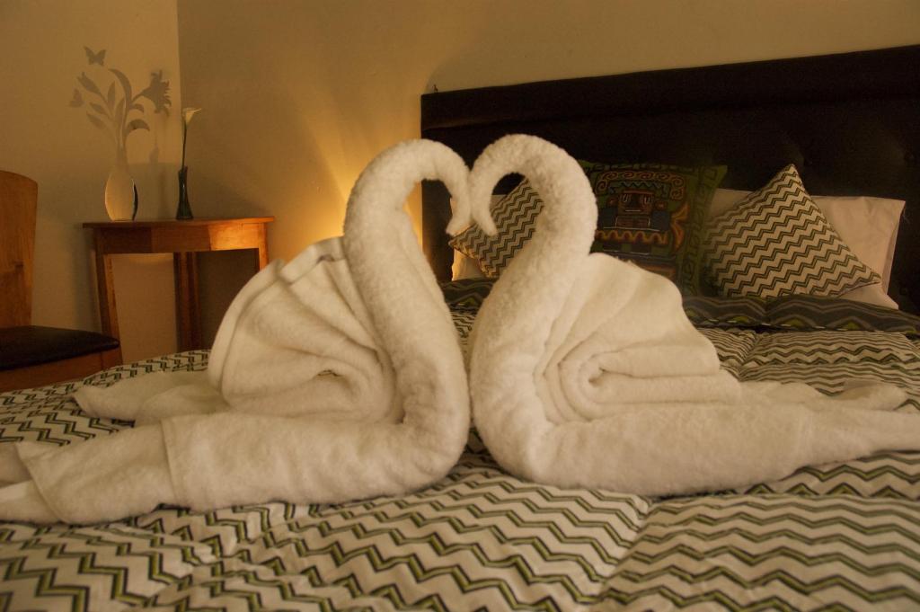 dos cisnes envueltos en toallas sentadas en una cama en Hotel Inka King, en Ollantaytambo