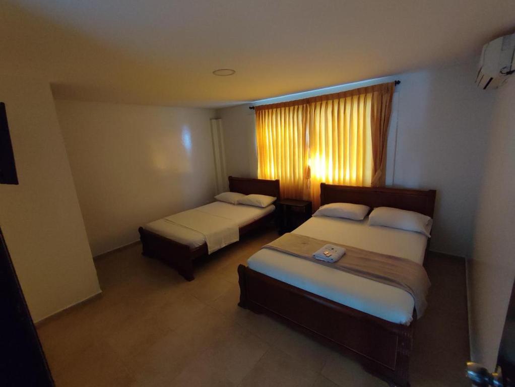 ein Hotelzimmer mit 2 Betten und einem Fenster in der Unterkunft Hotel Cinema in Bucaramanga
