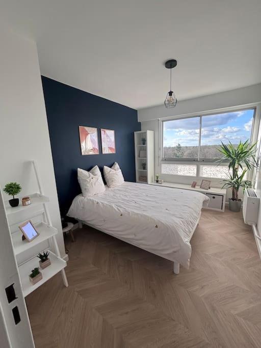 a bedroom with a large bed and a blue wall at Appartement T2 en résidence privée in Maurepas