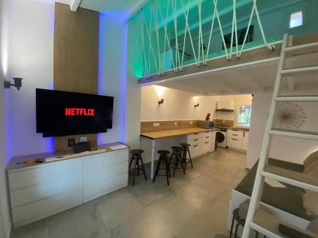 een keuken met een tv en een aanrecht met krukken bij Cap d'Agde Suit'Appart T2 Pinede 31 M2 in Cap d'Agde