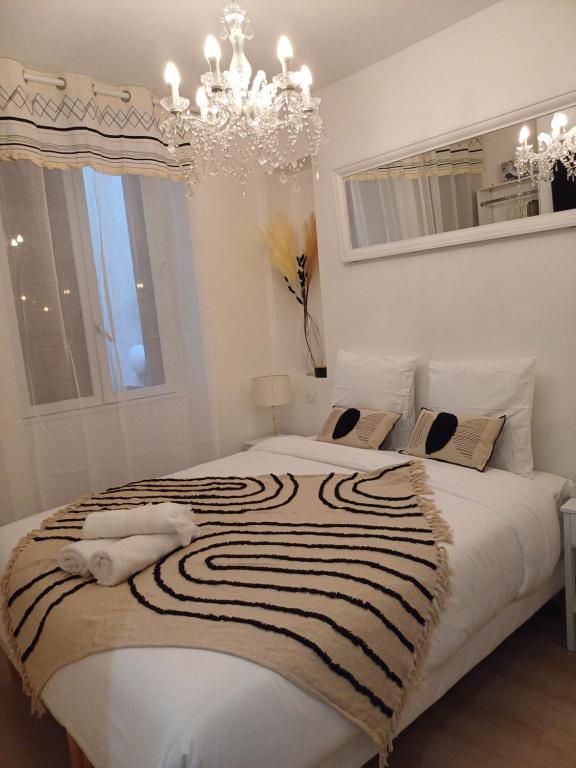 une chambre avec un grand lit blanc avec un lustre dans l'établissement *Cazotte Zola *, à Dijon